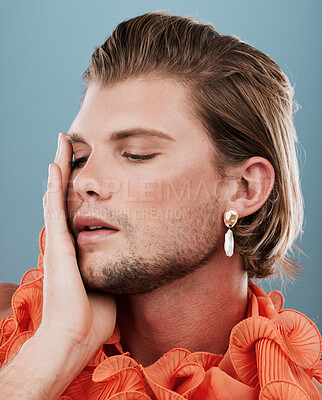 Buy stock photo LGBTQ, fashion and face of queer man with orange clothes, accessories and facial cosmetics on blue background. Transgender, gay or non binary model with beauty makeup, skincare glow or creative style