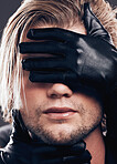 Fashion, beauty and model with leather gloves on his face in a studio with edgy, punk and trendy style. Non binary, LGBTQ and closeup of a man with a luxury, fancy or stylish dark aesthetic.