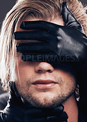 Buy stock photo Fashion, beauty and model with leather gloves on his face in a studio with edgy, punk and trendy style. Non binary, LGBTQ and closeup of a man with a luxury, fancy or stylish dark aesthetic.