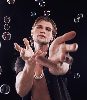 Buy stock photo Man, studio portrait and bubbles with for magic, art performance or creative show by black background. Model, hands and soap with rainbow light, dark mystery aesthetic and sexy fashion by backdrop