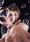 Man hands, bubbles and magic portrait in studio for art performance, creative show and black background. Model focus, sexy magician and soap with rainbow light, dark aesthetic or theater presentation