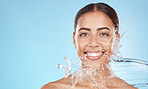 Happy woman, face skincare or water splash on blue background studio in healthcare wellness, hygiene maintenance or grooming mockup. Smile portrait, beauty model and facial water drop in wet cleaning