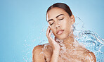 Woman, hand and water splash for face skincare, dermatology wellness or Brazilian healthcare grooming on blue background studio. Beauty model, water drop or facial cleaning in wet hygiene maintenance
