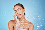 Woman skincare, hand or water splash face on blue background studio in healthcare wellness, Brazil hygiene maintenance or bathroom grooming. Beauty model, shower or wet water drop for facial cleaning