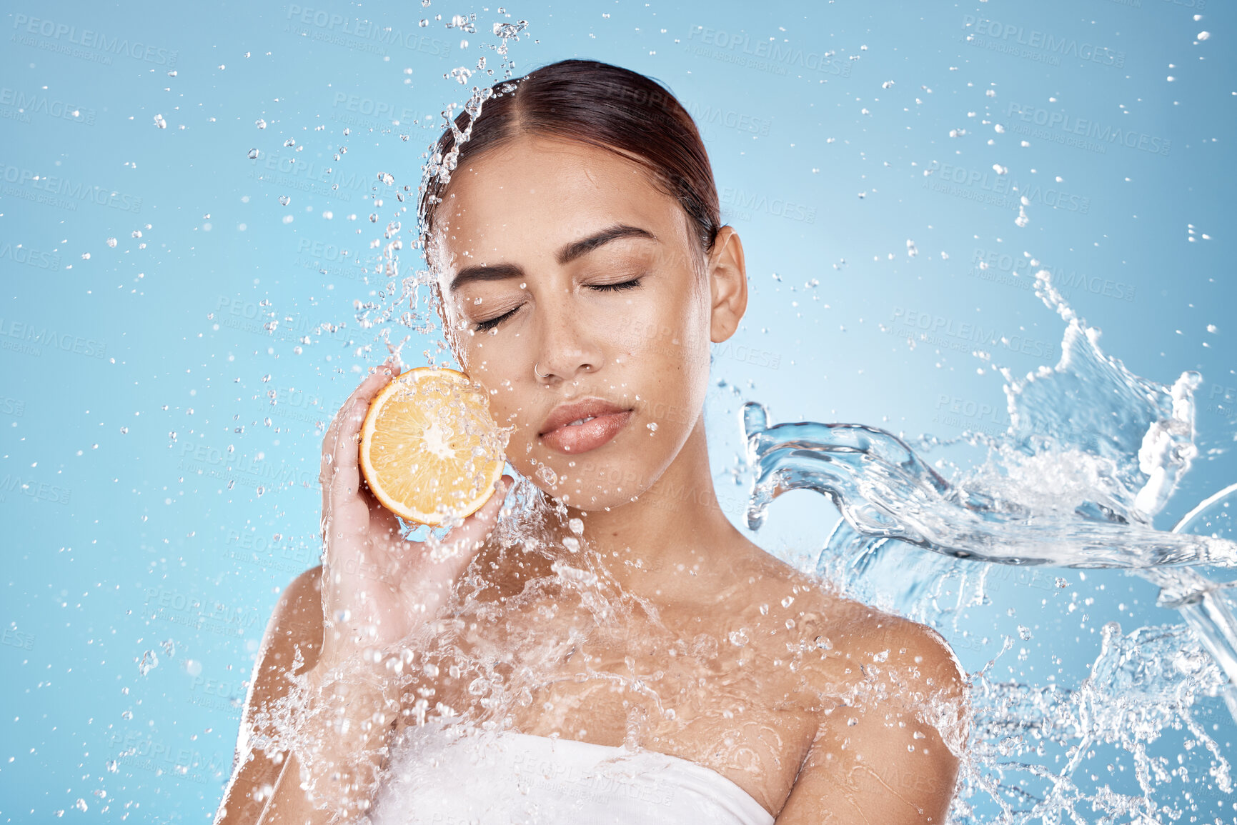 Buy stock photo Water splash, orange and natural skincare wellness in blue studio background for organic facial care cleaning, dermatology detox and fruit nutrition. Model face, citrus vitamin c and cosmetics clean