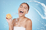 Water splash, beauty and woman, clean with orange for organic cosmetic care and hygiene in shower. Water, fruit and vegan skincare treatment with splash and excited female against studio background