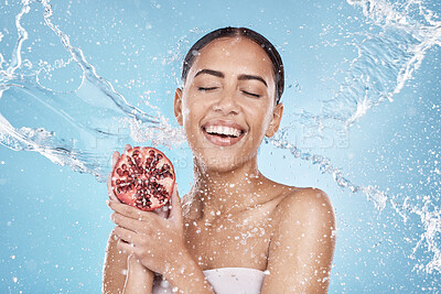 Buy stock photo Skincare, water splash and woman with a pomegranate in a studio for a healthy, organic and natural face treatment. Wellness, health and girl model with a fruit for a facial routine by blue background