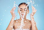 Woman, skincare or washing face with water splash on blue background studio for healthcare wellness, hygiene maintenance or bathroom grooming. Beauty model, hands or facial cleaning with water drops