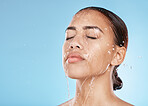 Woman, face skincare or water splash on blue background studio for healthcare wellness, Brazil hygiene maintenance or self care grooming. Beauty model, showering or wet water drop for facial cleaning