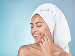 Woman, face and happy skincare with towel for luxury beauty, salon spa cleaning and closed eyes in blue background studio. Happy model, smile and skin glow, facial wellness or hair care dermatology