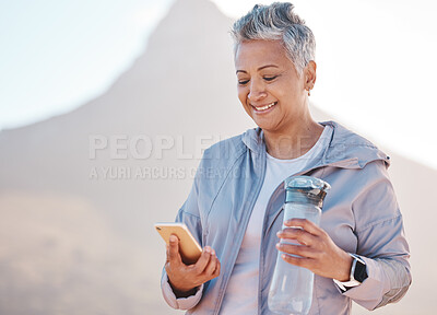 Buy stock photo Running, water and phone with senior woman in mountain for jogging, workout and cardio training. Social media, progress tracker and fitness app with runner on path checking mobile for endurance goals