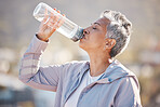 Fitness, health and senior woman drinking water for hydration on outdoor cardio run, exercise or retirement workout. Marathon training, bottle and profile of runner running in Rio de Janeiro Brazil