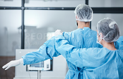 Buy stock photo Doctor, uniform and surgeon prepare for surgery, operation or medical healthcare. Nurse helping worker with safety clothing in emergency operating room, hospital and wellness support, theater or risk