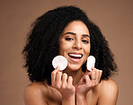 Face portrait, skincare and black woman with cotton in studio isolated on a brown background. Wellness, cosmetics and happy female model holding facial pad or product for cleaning makeup for hygiene.