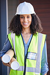Portrait, architect and blueprint with a black woman designer wearing a reflective vest and hardhat for construction. Building, architecture or safety with a female engineer holding plans indoors