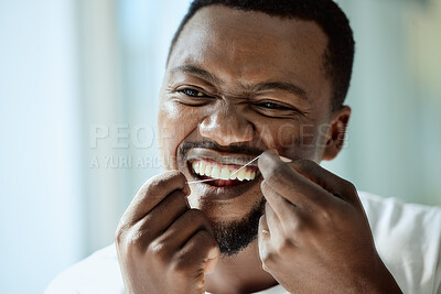 Buy stock photo Health, beauty and teeth of black man with dental floss for morning oral hygiene routine with focus. Dental care, self care and wellness of person cleaning and checking teeth in bathroom mirror.



