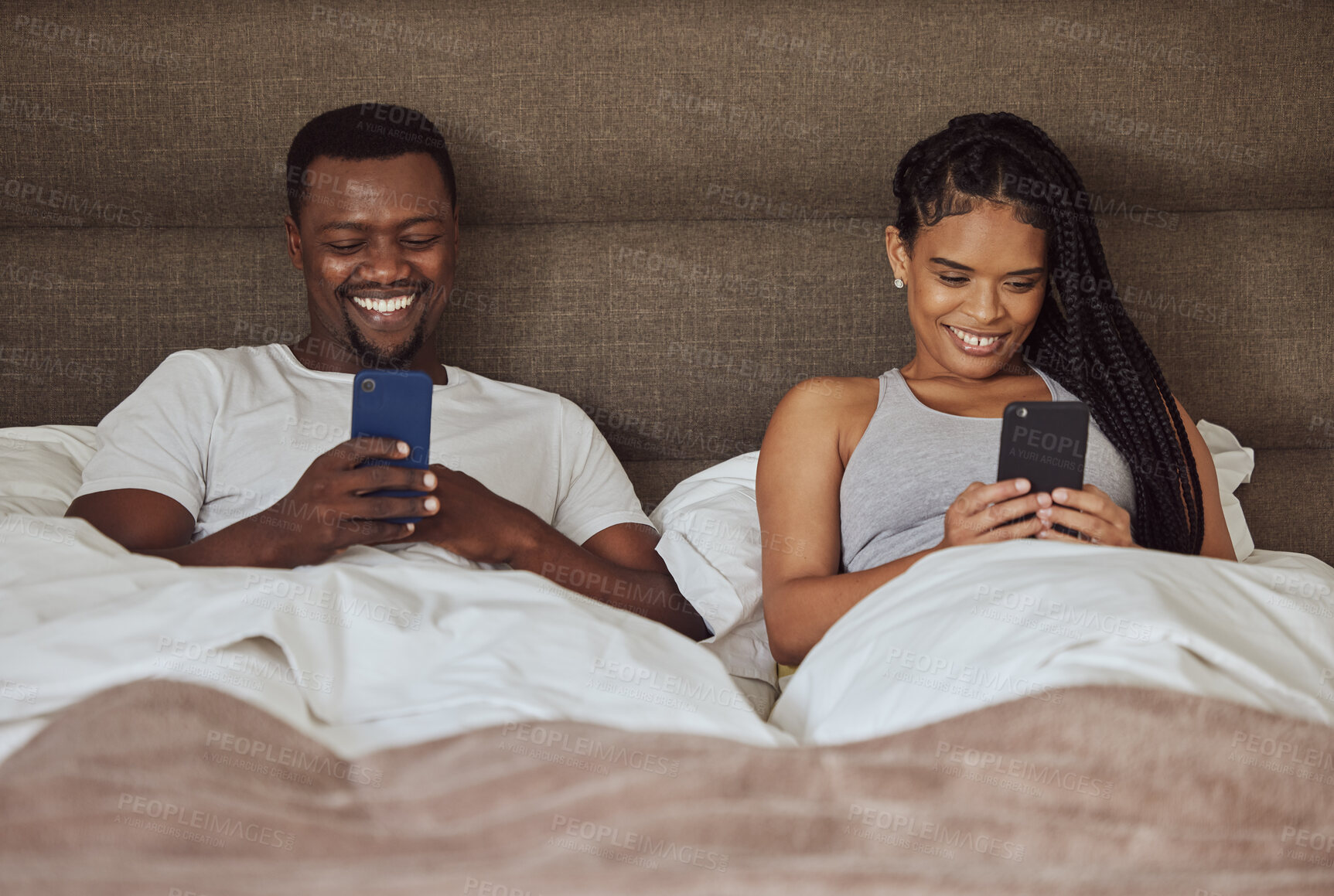 Buy stock photo Black couple, smartphone and happiness together in bed for social media streaming, relax quality time or reading online. African man smile, black woman and happy watching video on phone in bedroom