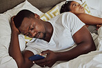 Phone, addiction and bedroom with a black couple lying in bed ignoring one another in the evening. Unhappy, upset and social media with a man and woman struggling from trouble or issues in their home