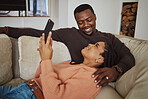 Black couple, phone and home wifi for internet connection while together on living room couch with love. Young man and woman talking while streaming internet or online for communication or ecommerce