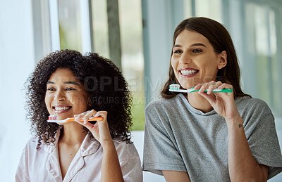 Buy stock photo Toothbrush, oral care and women friends doing a dental, health and wellness morning routine together. Happy, smile and interracial females brushing their teeth for mouth hygiene in the bathroom.