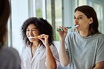 Toothbrush, dental hygiene and women friends doing a self care, health and wellness routine together. Happy, smile and interracial females doing oral care while brushing teeth in the bathroom at home