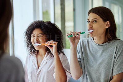 Buy stock photo Toothbrush, dental hygiene and women friends doing a self care, health and wellness routine together. Happy, smile and interracial females doing oral care while brushing teeth in the bathroom at home