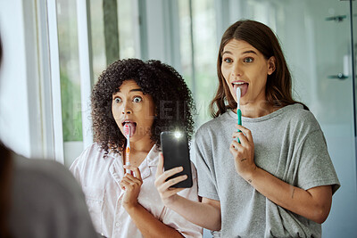 Buy stock photo Friends, wellness and brushing teeth phone selfie with crazy face for morning hygiene routine in home. Comic, goofy and interracial friendship of women cleaning teeth with smartphone photograph.