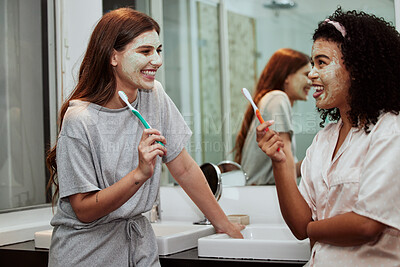 Buy stock photo Face mask, tooth brush and women friends doing a self care, health and wellness routine together. Happy, smile and interracial females doing skincare treatment while brushing teeth in the bathroom.