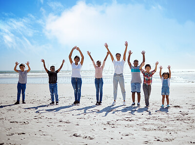 Buy stock photo Children, beach and friends in summer with their arms raised while standing on the sand by the sea or ocean. Portrait, kids and gesture with a boy and girl friend group by the coastal water