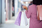 Woman, shopping bag and walking in a mall for retail therapy, sale and customer discount at a store. Hand of fashion female at commercial shop buying clothes on promotion for commerce on travel