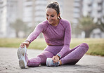 Exercise, woman and city fitness while stretching on floor outdoor at a park for health and wellness. Athlete female sitting for warm up workout and running for healthy lifestyle, energy and body