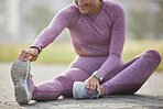 Woman, exercise and fitness while stretching outdoor at a city park for health and wellness with cardio training. Athlete female sitting for warm up workout and running for healthy lifestyle and body