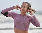 Fitness, woman with earpods for music during run at beach, exercise and training for marathon with podcast or radio streaming. Happy runner, female and listening with workout in nature and wellness