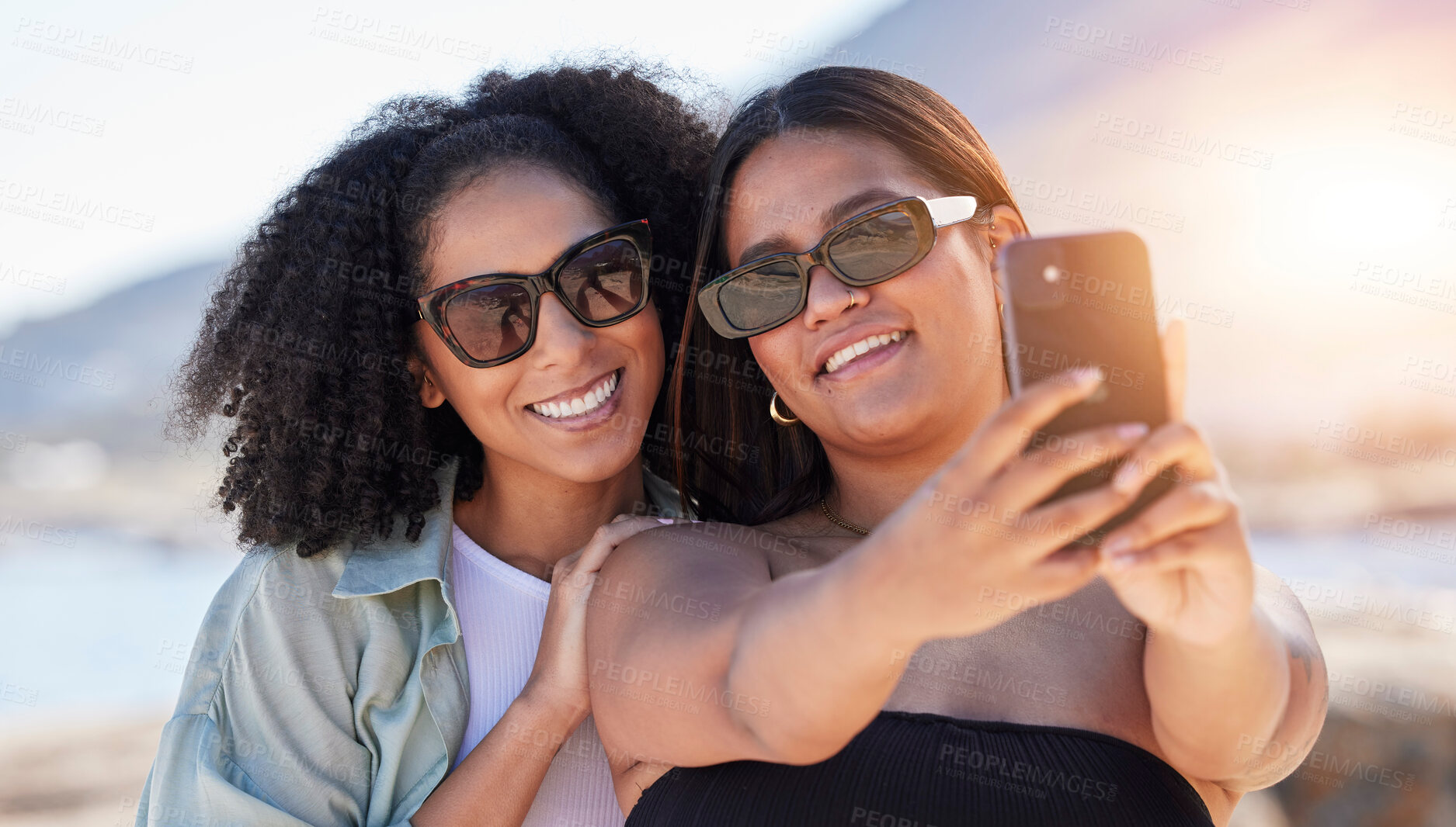 Buy stock photo Women, lgbtq and phone selfie at beach for love, travel and care on summer holiday, vacation or freedom. Sunglasses, lesbian and happy couple of friends taking mobile photograph, sea and social media