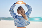 Heart, hands and back view of woman at beach love, care and kindness, trust and support. Girl, sea and finger shape for wellness, nature and peace for earth day, blue sky and ocean travel in sunshine