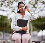 Headphones, black woman and outdoor for peace, happiness and audio with young lady calm in park. African American female, student or girl with folder, headset for podcast or streaming music in nature