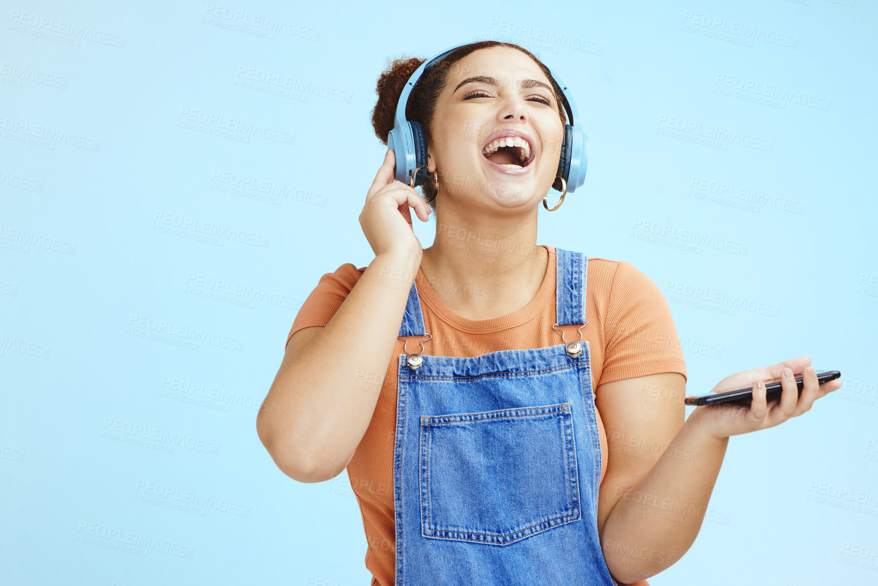 Buy stock photo Mockup, headphones and woman with smartphone, happy or connection on blue studio background. Fun, female or girl laughing, cellphone for music or headset for podcast, online streaming or social media