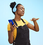 Black woman, music and phone in studio with dance, dj hand gesture and listening by blue background. Gen z girl, streaming audio or online radio on internet, happy and fashion headphones by backdrop