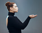 Hand, woman and holding gesture in studio with mockup, space and grey background for product placement. Young, beautiful and girl with open palm hands on mock up, branding and showing copy space