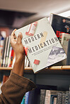 Book in hand, library and student of medicine, pills and healthcare education and learning about pharmaceutical drugs. Black woman with reading information, learn and study, research for medical test