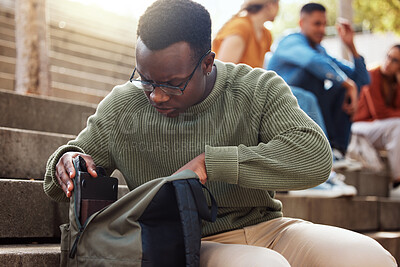 Buy stock photo University, student and black man looking in bag at campus for learning, studying or lost knowledge book. College steps, scholarship and male checking or searching backpack for missing item outdoors.