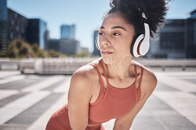 Buy stock photo Fitness, headphones and rest, woman runner stop to relax or breathe on city run or workout. Health, urban training and wellness, a tired black on break from running exercise while streaming music app