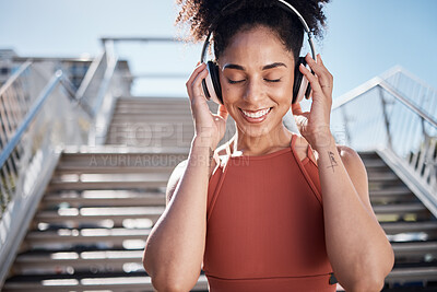 Buy stock photo Fitness, music headphones and black woman in city streaming radio or podcast. Face, sports meditation and happy female athlete listening to song or audio outdoors by stairs after training or workout