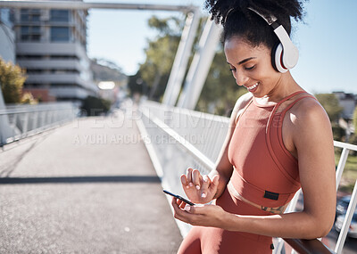 Buy stock photo Fitness, headphones and black woman with phone in city for social media or texting. Sports, exercise and happy female on break streaming music, radio or podcast on 5g mobile smartphone after training