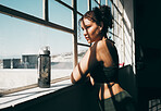 View, exercise and relax with a sports woman looking out of a window during a break in the gym for fitness. Health, wellness and training with a female athlete taking a break from her studio workout