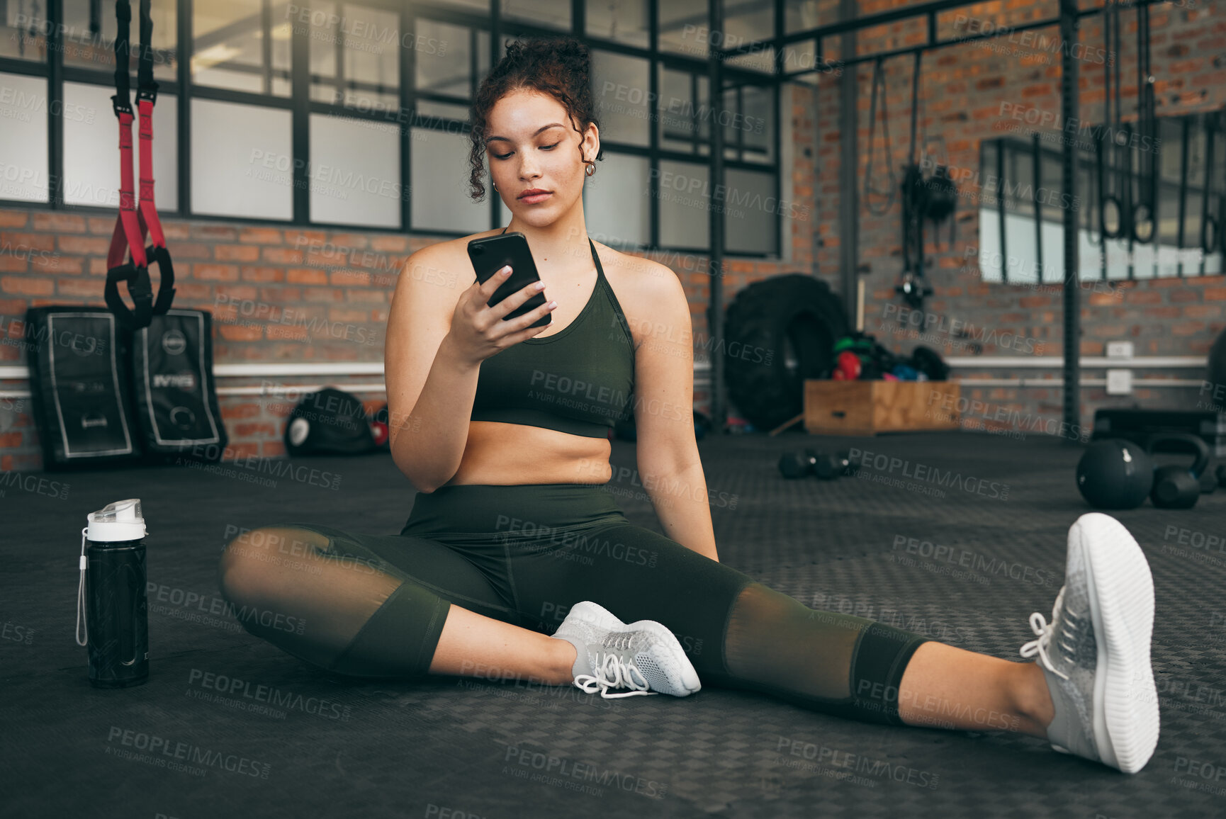 Buy stock photo Fitness, phone and woman at gym for a workout, training and body wellness with a mobile app. Young sports female with smartphone for progress, performance and communication for a healthy lifestyle