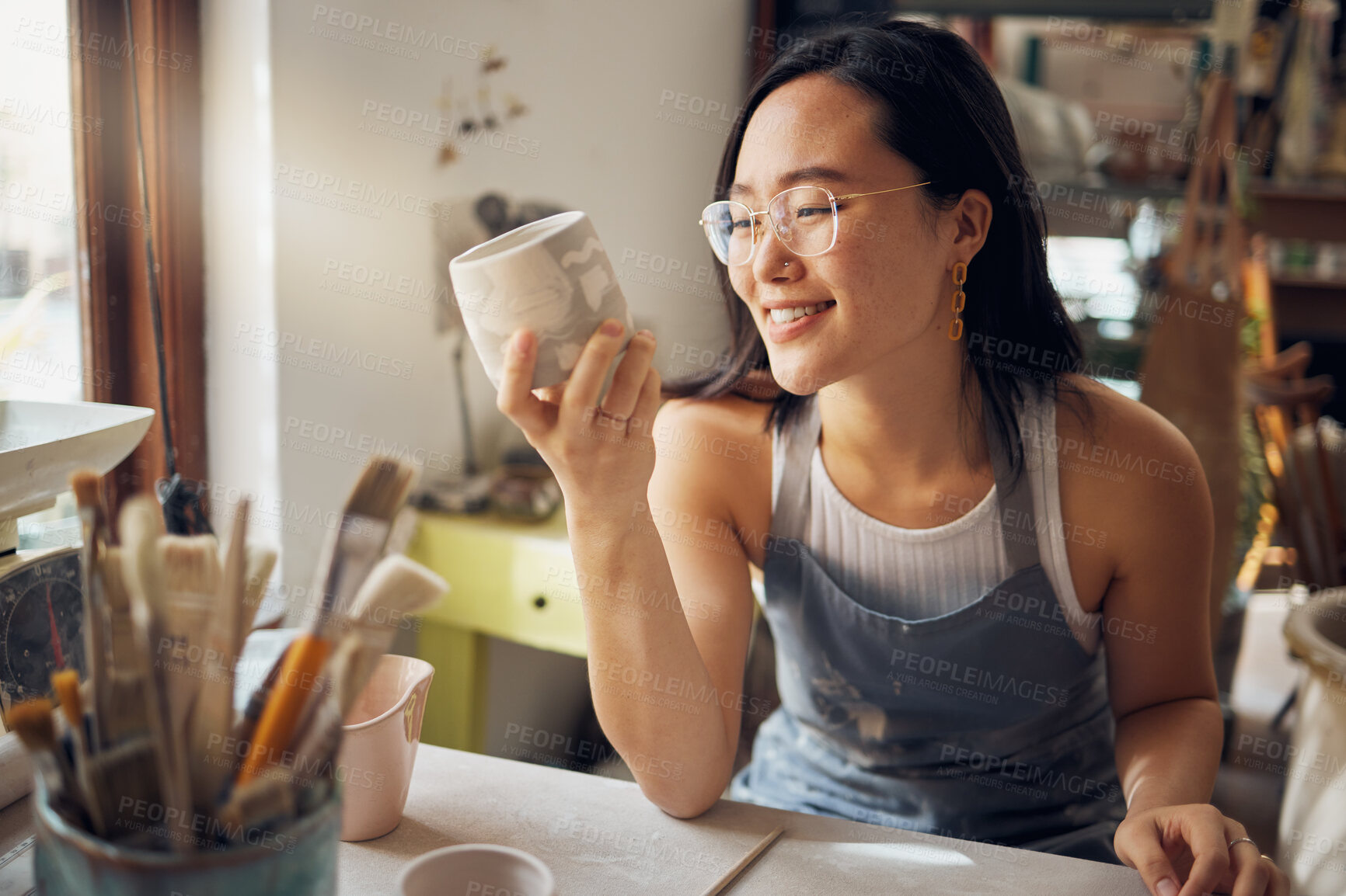 Buy stock photo Artist, Asian and woman as small business entrepreneur happy about design and product at a workshop. Pottery, mug and clay sculpture by creative startup female smiling and satisfied by art