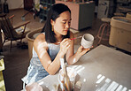 Pottery, art and ceramics with an asian woman in a studio for design or a creative hobby as an artisan. Manufacturing, pattern and artist with a female potter sitting in her workshop  as a sculptor