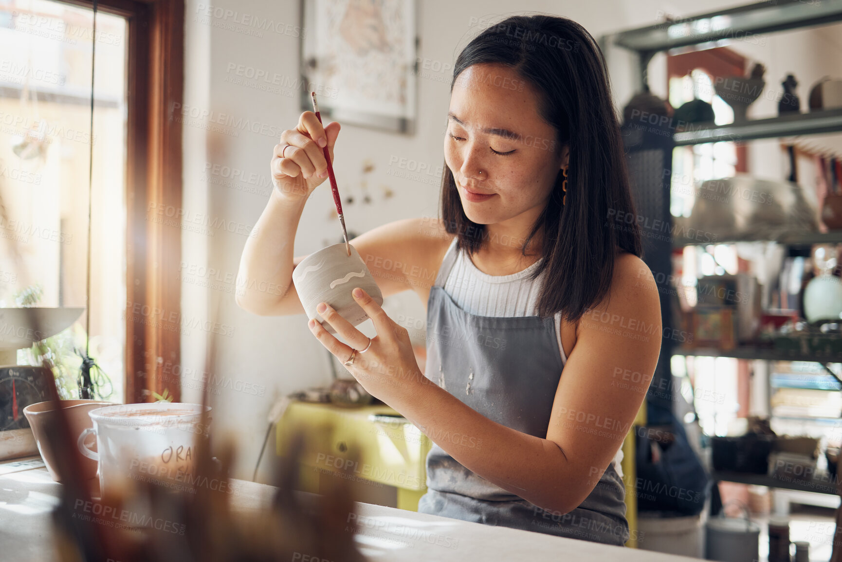Buy stock photo Pottery, art and design with an asian woman in a studio for her creative ceramics hobby as an artisan. Manufacturing, pattern and artist with a female potter sitting in her workshop  as a sculptor