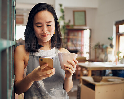 Buy stock photo Artist woman, phone and reading chat with coffee, smile and focus on email, app or social media for date. Asian art entrepreneur, social network and smartphone with happiness, tea and relax in studio